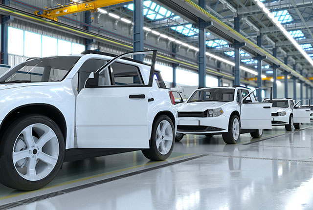 An automotive manufacturing plant with four manufactured cars in a row