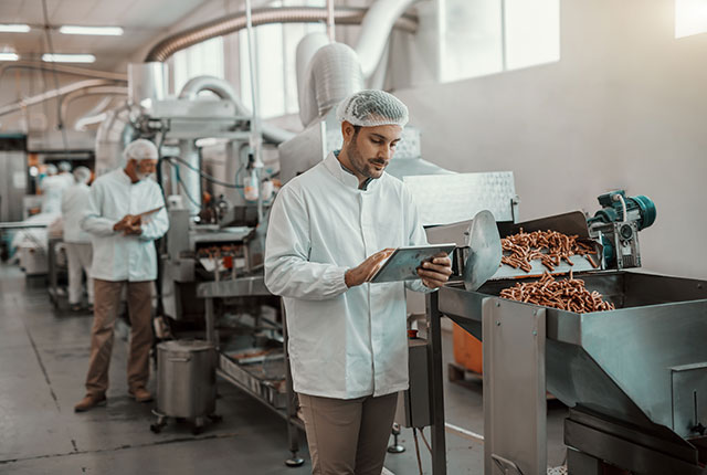Man using a tablet inside of a food processing plant